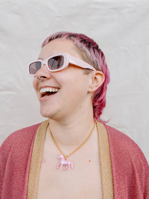 Model Laughing While Wearing Pink Pony Pendant Necklace With Gold Chain